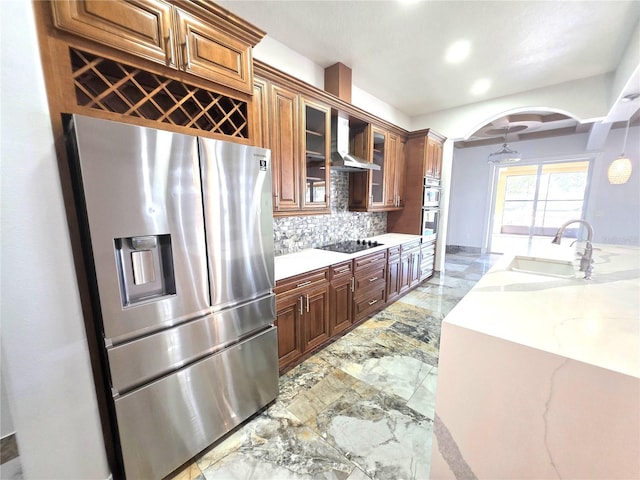 kitchen with a sink, appliances with stainless steel finishes, wall chimney range hood, marble finish floor, and backsplash