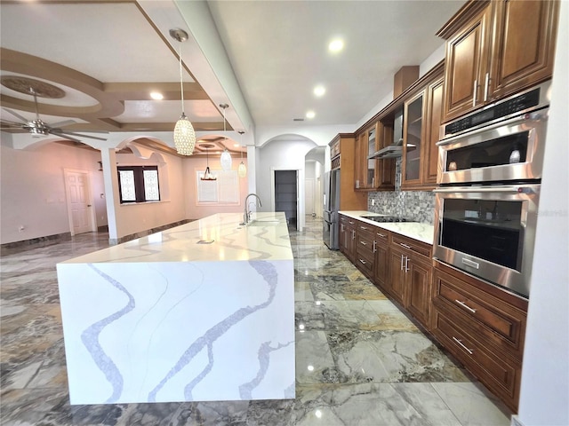 kitchen with backsplash, ceiling fan with notable chandelier, appliances with stainless steel finishes, arched walkways, and marble finish floor