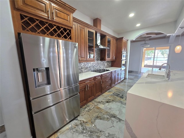 kitchen featuring backsplash, marble finish floor, stainless steel appliances, wall chimney exhaust hood, and a sink