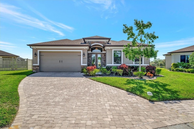 prairie-style home with a front yard, french doors, decorative driveway, stone siding, and an attached garage