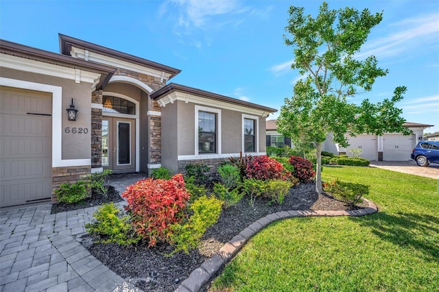 property entrance featuring stone siding, stucco siding, a lawn, and a garage