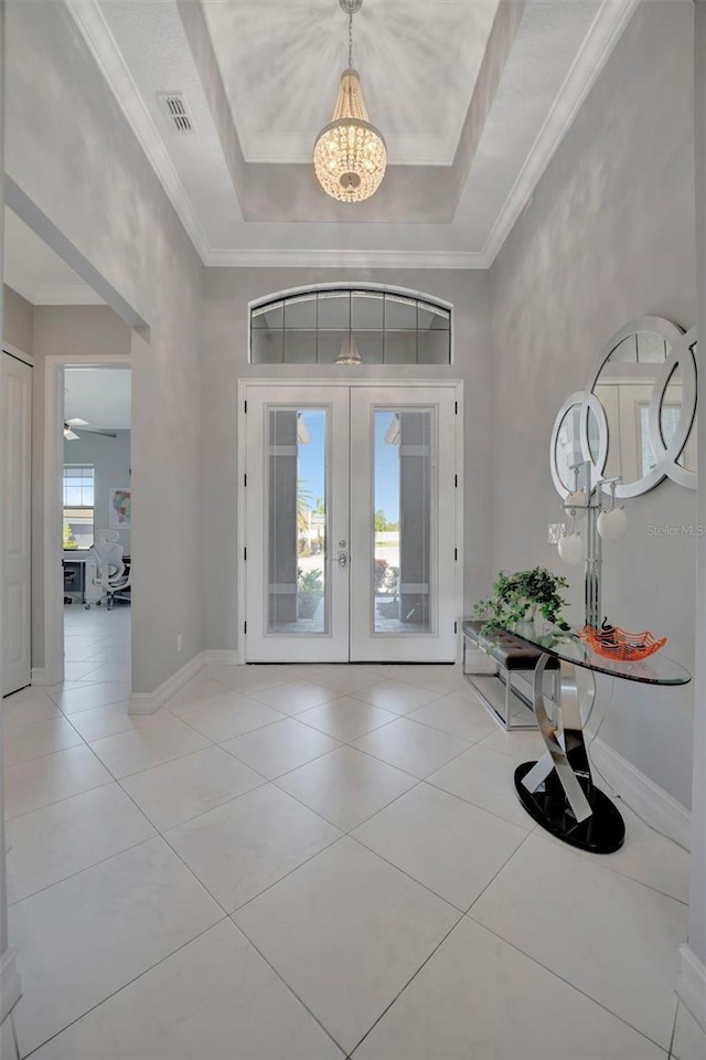 foyer featuring french doors, a raised ceiling, visible vents, and ornamental molding