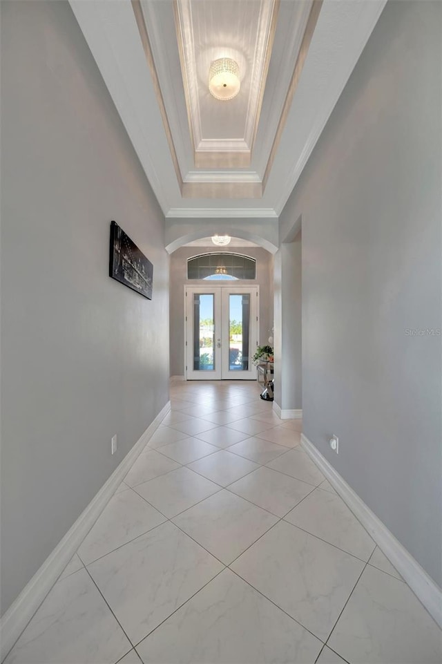 corridor featuring crown molding, french doors, baseboards, and a raised ceiling