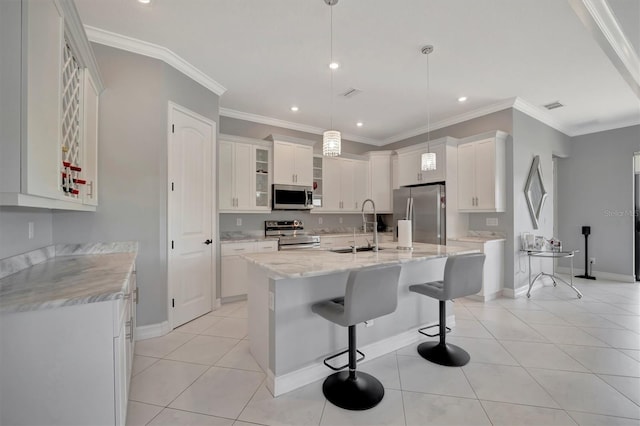 kitchen featuring light tile patterned floors, a center island with sink, a sink, stainless steel appliances, and a kitchen bar