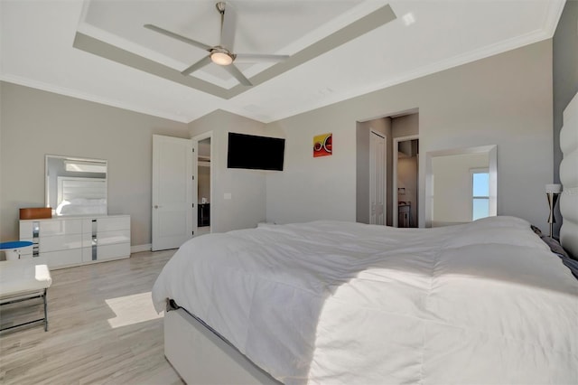 bedroom featuring light wood finished floors, baseboards, a tray ceiling, ornamental molding, and a ceiling fan