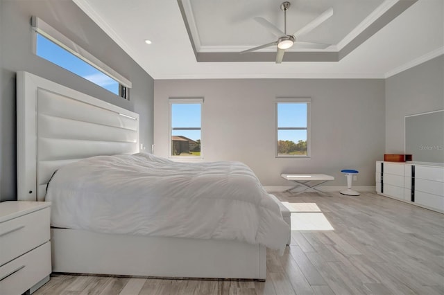 bedroom featuring a raised ceiling, light wood-style floors, and ornamental molding