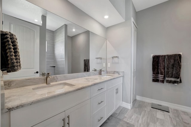 bathroom with a sink, baseboards, recessed lighting, and double vanity