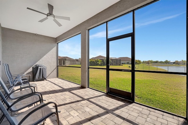 unfurnished sunroom with a water view and ceiling fan