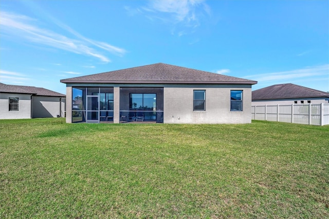 rear view of property featuring a yard, fence, a sunroom, and stucco siding