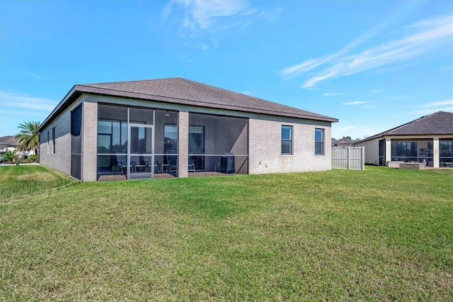 rear view of property featuring a lawn, a sunroom, and stucco siding