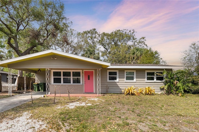 single story home featuring a carport, concrete driveway, a front lawn, and fence