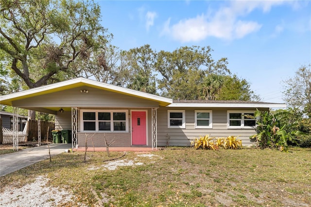 view of front of house featuring a front lawn, an attached carport, fence, concrete driveway, and brick siding