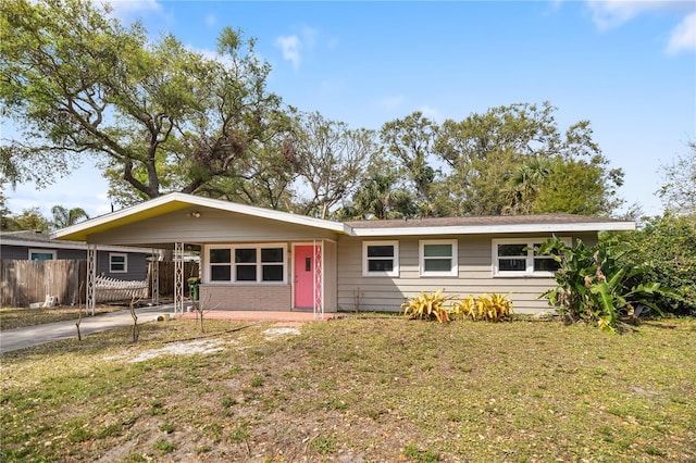 ranch-style house featuring an attached carport, fence, a front lawn, and driveway