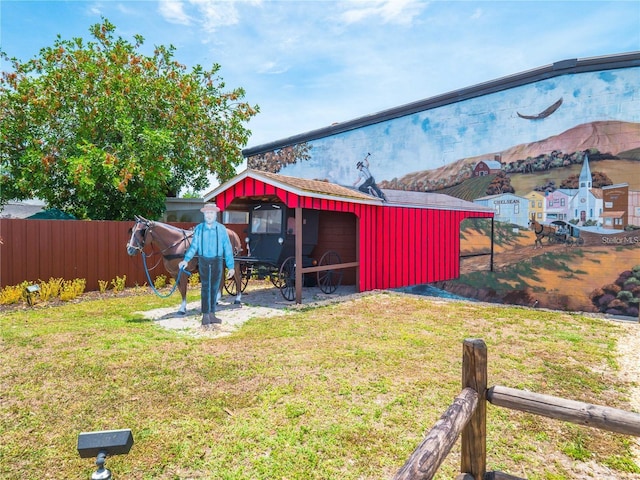 view of yard featuring an outbuilding, a pole building, and fence