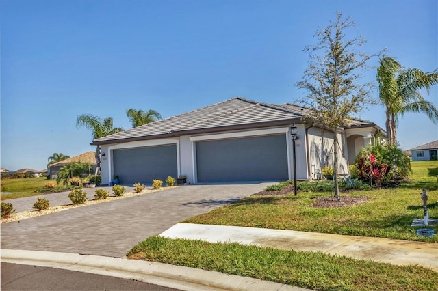 view of front of house with stucco siding, a tiled roof, decorative driveway, and a garage