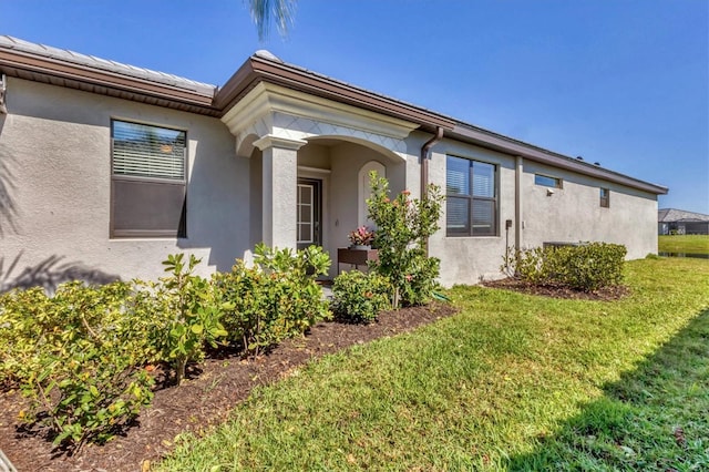 exterior space featuring stucco siding, a tiled roof, and a front yard