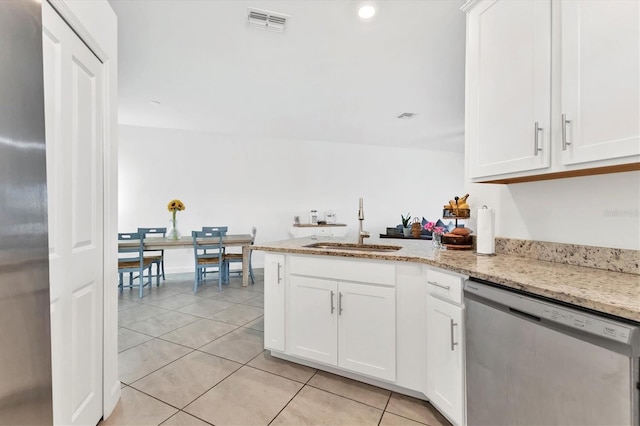 kitchen with light tile patterned floors, a peninsula, a sink, white cabinets, and appliances with stainless steel finishes
