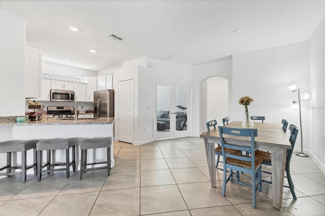 kitchen with arched walkways, visible vents, appliances with stainless steel finishes, and light tile patterned flooring