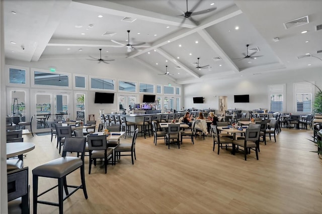 dining area with high vaulted ceiling, light wood-style floors, visible vents, and ceiling fan