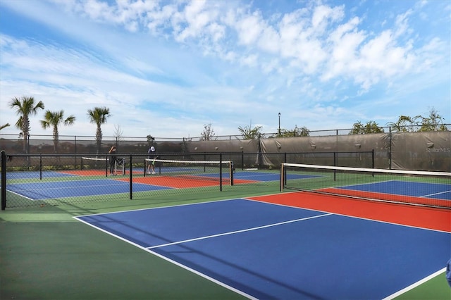 view of tennis court featuring community basketball court and fence