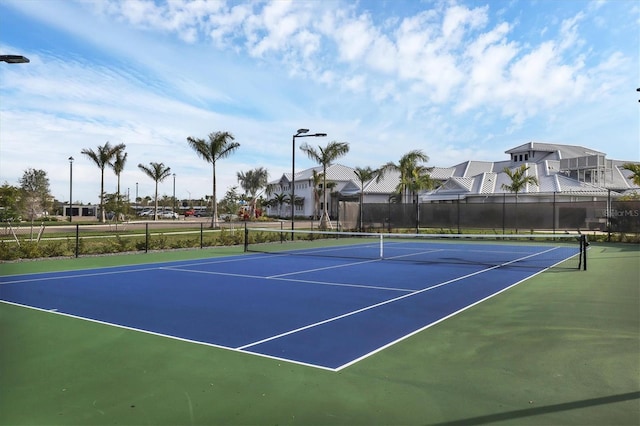 view of tennis court featuring a residential view, community basketball court, and fence