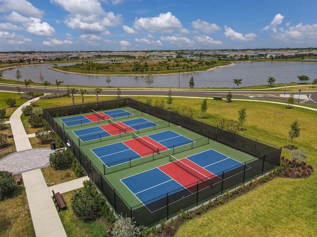 exterior space featuring a tennis court, a water view, a yard, and fence