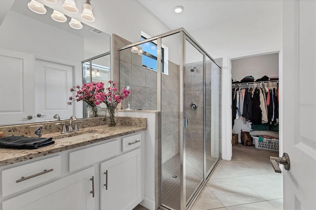 full bathroom with a spacious closet, a shower stall, tile patterned floors, and vanity