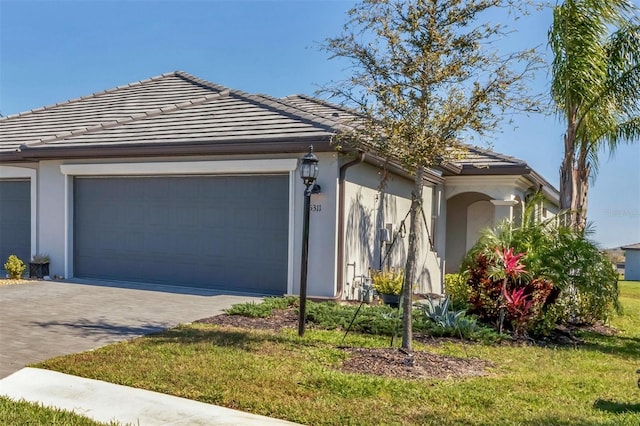 exterior space with a front yard, driveway, an attached garage, stucco siding, and a tiled roof