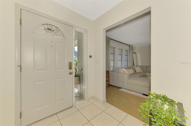 foyer entrance with light tile patterned floors and baseboards