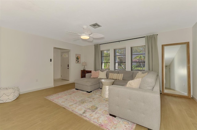 living area featuring light wood finished floors, visible vents, baseboards, and a ceiling fan