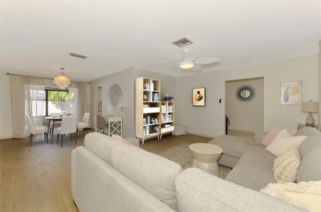 living room with visible vents, ceiling fan with notable chandelier, and light wood-style floors