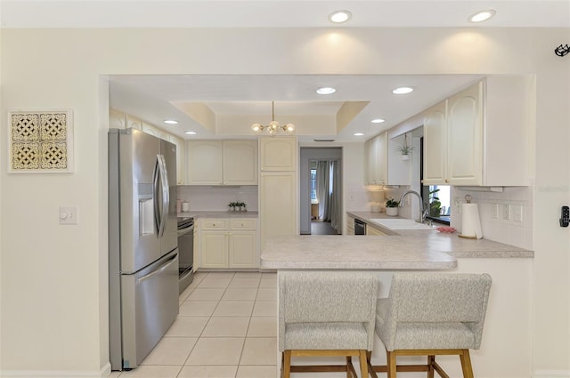 kitchen with a peninsula, electric range, stainless steel fridge with ice dispenser, a sink, and a raised ceiling