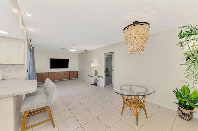 living room with light tile patterned floors, recessed lighting, ceiling fan with notable chandelier, and baseboards