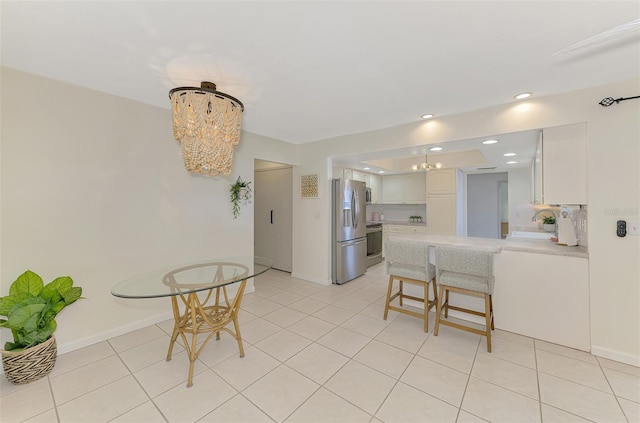 kitchen with a sink, white cabinetry, appliances with stainless steel finishes, a peninsula, and an inviting chandelier