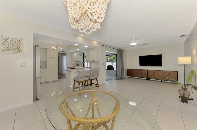 living area featuring light tile patterned floors, baseboards, visible vents, recessed lighting, and ceiling fan with notable chandelier