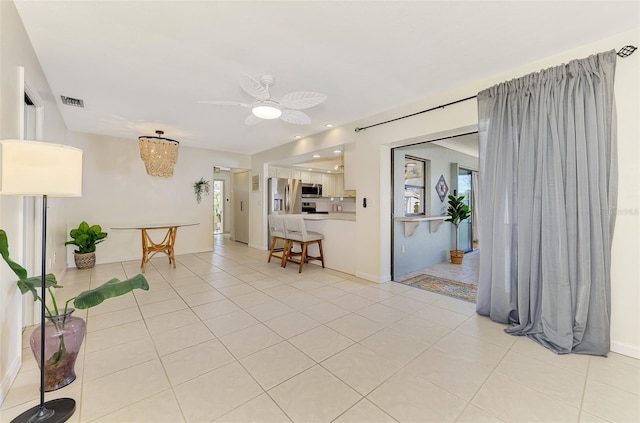 interior space with light tile patterned flooring, a ceiling fan, visible vents, and baseboards