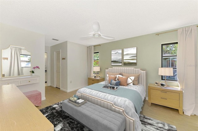 bedroom featuring visible vents, light wood-style flooring, a ceiling fan, a textured ceiling, and baseboards