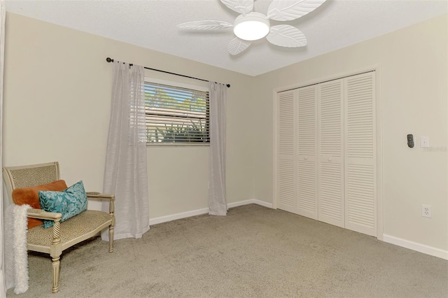 sitting room featuring carpet, baseboards, and ceiling fan