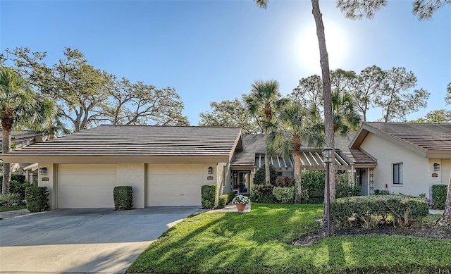 view of front facade featuring stucco siding, a garage, concrete driveway, and a front lawn