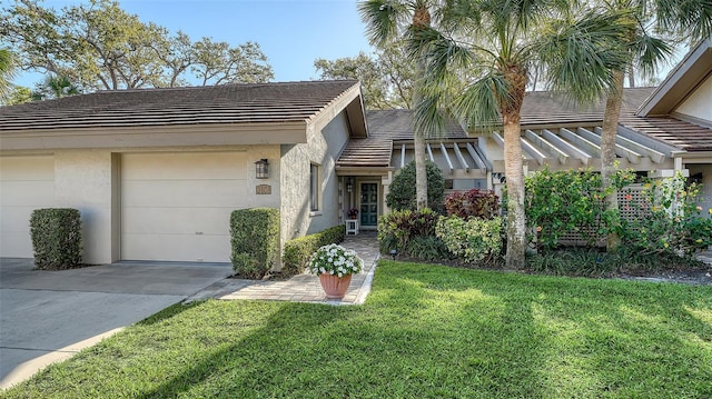 view of front of home featuring a front yard, an attached garage, a tile roof, and stucco siding