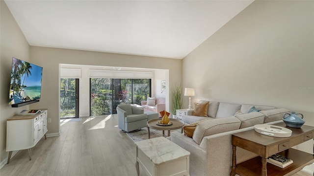 living room featuring baseboards, lofted ceiling, and light wood-style floors