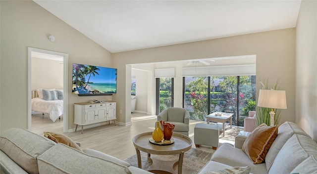 living area with baseboards, lofted ceiling, light wood-style flooring, and a ceiling fan