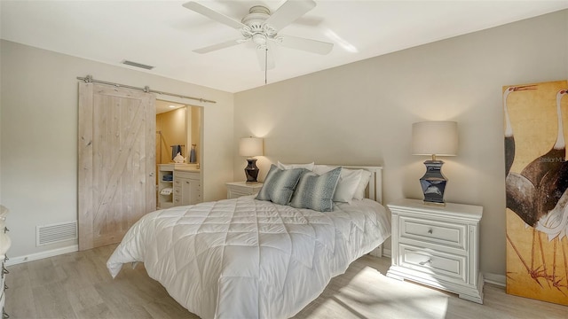 bedroom featuring a barn door, visible vents, and light wood-type flooring