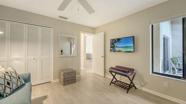 living area with light wood finished floors, visible vents, baseboards, and ceiling fan