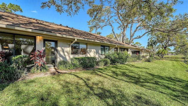 rear view of property with a lawn and stucco siding