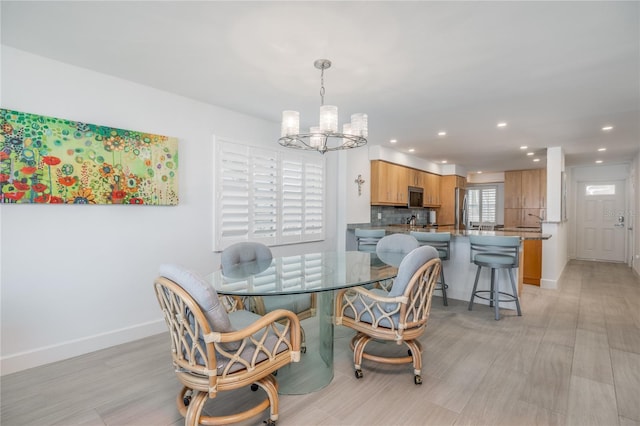 dining area with a notable chandelier, recessed lighting, light wood-style floors, and baseboards