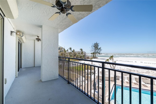 balcony featuring a view of the beach and a ceiling fan