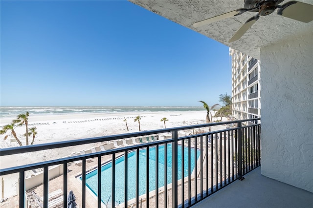 balcony with a water view, a ceiling fan, and a view of the beach