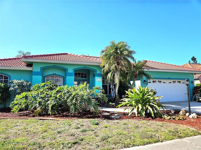 mediterranean / spanish home with a tile roof, concrete driveway, an attached garage, and stucco siding