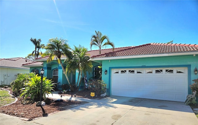 view of front of home featuring stucco siding, concrete driveway, a tile roof, and a garage